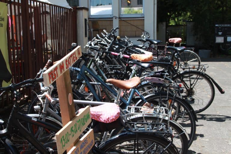 Viele Fahrräder in einer Reihe, davor ein Schild mit der Aufschrift "Fest im Sattel"